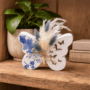 Opengewerkte vlinder decoratie met droogbloemen Decoratieve opengewerkte vlinder van porseleingips met blauwe bloemen decoupage en droogboeketje