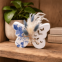 Opengewerkte vlinder decoratie met droogbloemen Decoratieve opengewerkte vlinder van porseleingips met blauwe bloemen decoupage en droogboeketje