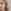 Rode Hart Oorstekers – Liefdevol Cadeau voor vrouwen Close-up van een jonge vrouw met golvend blond haar die een rode oorsteker in de vorm van een hartje met details draagt.