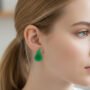Groene Peren Oorstekers - Fruitige Sieraden Close-up van een blond model met een paardenstaart die groene peren oorstekers (12x19mm) draagt, vierkant formaat.