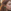 Close-up van een roodharige vrouw met een bloemenkrans die een felgroene oorsteker in de vorm van een cannabisblad (marihuanablad) draagt.