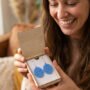 Vrouw blij met Oorbellen in Houten Cadeau Doosje Lachende vrouw toont geopende houten doosje met blauwe oorbellen als cadeau