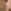 Close-up van een vrouw met golvend blond haar die een ruitvormige oorbel draagt aan een haakje. De oorbel heeft een ruitvormig ontwerp, met een witte ruit in het midden omrand door een rode rand.