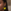 Close-up van het oor en de wang van een vrouw met lang donker haar, die een felgele, vlindervormige druppeloorbel aan een zilveren haakje draagt.