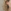 Zwarte Vrolijke Stickman Oorbel Close-up van het oor van een vrouw met golvend blond haar die een zwarte, druppelvormige oorbel draagt in de vorm van een vrolijke stickman met een glimlachend gezicht.