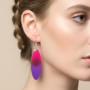 Lange Resin Oorbellen Roze-Paars – Handgemaakte Sieraden – Lifestyle Look Close-up van een vrouw die een lange, ovale handgemaakte resin oorbel draagt met een kleurverloop van fuchsia roze naar paars.