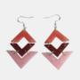 Handgemaakte geometrische oorbellen bestaande uit drie in elkaar grijpende ruitvormen in de kleuren terra, donkerbruin en lichtroze met een subtiele glitterafwerking aan zilverkleurige haakjes.