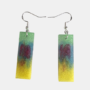 Lange Multicolor Glitter Oorbellen Rechthoek Handgemaakte lange rechthoekige oorbellen van kunsthars met een verticaal kleurverloop van groen naar blauw en geel inclusief paarse details en zilveren haakjes.