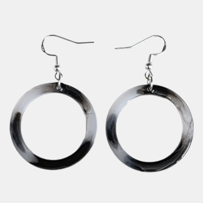 Zwart-wit gemarmerde ronde hanger oorbellen met zilverkleurige haken op een witte achtergrond.