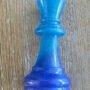 Blauwe-epoxy-koning-schaakstuk-detail. Detailopname van een handgemaakte blauwe epoxy schaakstuk koning met glinstering op een houten achtergrond.