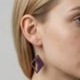 model draagt paarse geometrische epoxy oorbel ruitvormig Model met blond haar en groene ogen draagt een paarse ruitvormige epoxy oorbel