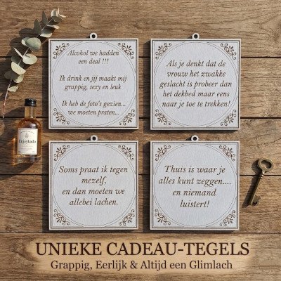 Vier vierkante decoratieve tegeltjes met grappige Nederlandse teksten op een houten achtergrond, geflankeerd door een flesje drank en een antieke sleutel