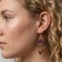 Dichtbij opname van een vrouwelijk model met blond krullend haar die een ruitvormige paars-gouden glitteroorbel draagt