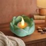 groen-epoxy-lotus-kaars-knus Groen epoxy lotus schaaltje met flakkerende LED LED LED-kaars op een houten nachtkastje in een knusse slaapkamer.