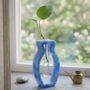 Blauwe epoxy stekjeshouder met Pothos plant. Blauwe epoxy vaas met organische vorm en glazen testbuis voor stekjes op vensterbank.