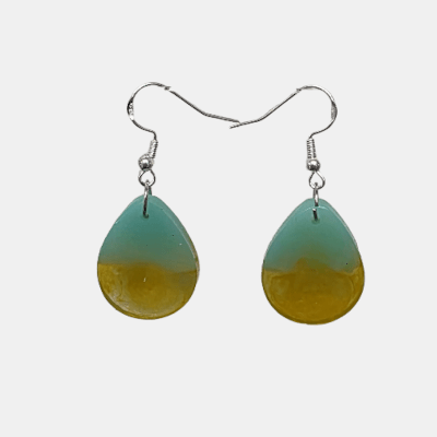 Handgemaakte epoxy oorbellen in druppelvorm met mintgroene en okergele kleuren, hangend aan zilverkleurige haken.